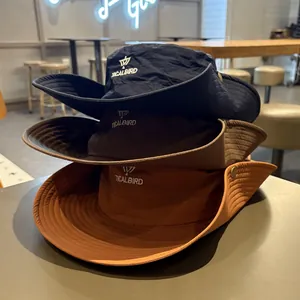 Three stacked outdoor sunshade hiking bucket hats in navy, brown, and orange colors