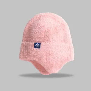 Detailed view of pink knitted beanie with soft ear protection and snowflake tag