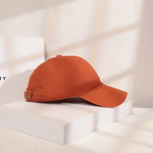 Seitenansicht einer hochwertigen burnt-orangefarbenen Baumwoll-Basecap auf weißem Sockel.