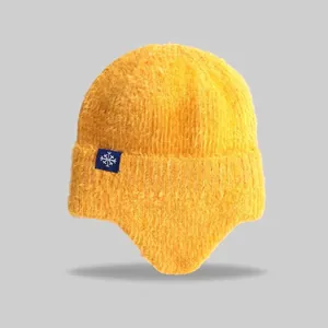 Close-up of yellow knit earflap beanie with snowflake tag detail