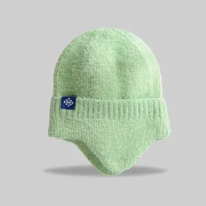 Detailed view of a cozy mint green knit winter beanie featuring ear flaps and a snowflake tag