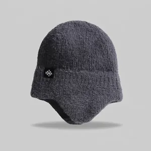 Close-up of grey winter knitted hat with warm ear flaps and snowflake detail