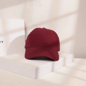 Detailansicht einer burgunderroten Baumwoll-Basecap auf einem eleganten weißen Ständer