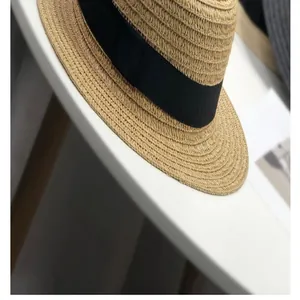 Vue détaillée de la texture tissée d'un canotier en paille pour femme avec ruban noir.