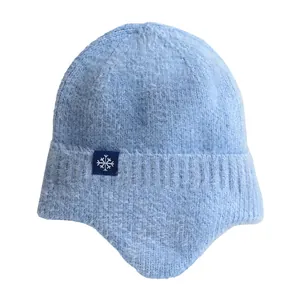 Warm light blue knitted winter beanie with ear flaps and snowflake detail