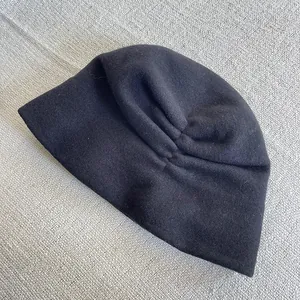 Close-up detail of the elegant black pleated Australian wool hat for winter