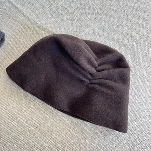 Close-up of dark brown wool slouchy hat with pleated details for winter warmth