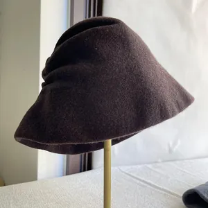 Detailed side view of an elegant dark brown wool bucket hat featuring a unique pleated design