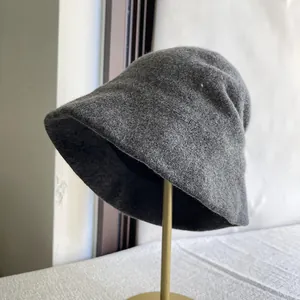Close-up detail of a dark grey Australian wool bucket hat on a gold display stand