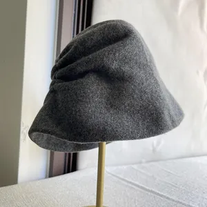 Close-up detail of a dark grey wool slouchy bucket hat on a gold display stand