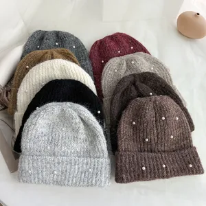 Close-up detail of cozy winter knitted beanies featuring elegant white pearl embellishments