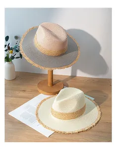 Detailed view of two color-blocked straw sun hats with retro frayed edges on a wooden table.
