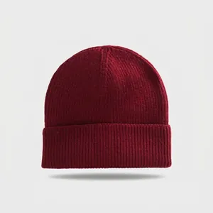 Close-up detail of burgundy knitted beanie showing thick ribbed texture and folded brim
