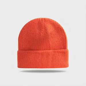 Close-up of bright orange knitted beanie with ribbed texture and folded brim cuff