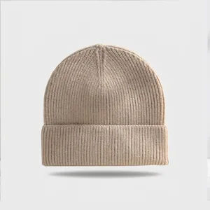 High-quality close-up detail of a beige ribbed knit beanie featuring a classic folded cuff.