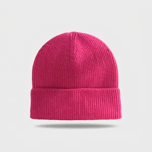 Close-up of bright pink knitted beanie showing soft ribbed texture and cuffed design.