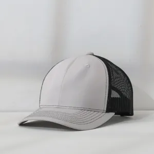 Detail of a two-tone mesh trucker hat in light grey and black with structured panels.