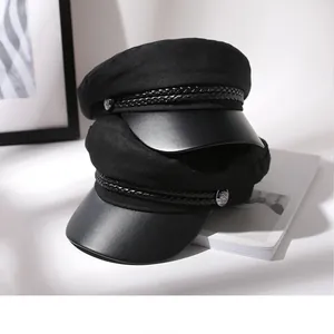 Detailed shot of two black newsboy caps featuring braided rope bands and leather brims