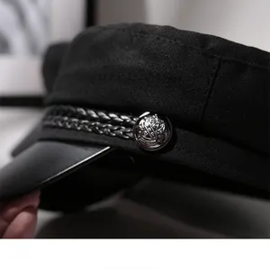 Macro detail view of black newsboy sailor hat showing braided rope and crest metal button
