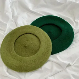 Detail view of high-quality wool fabric on olive and forest green beret hats