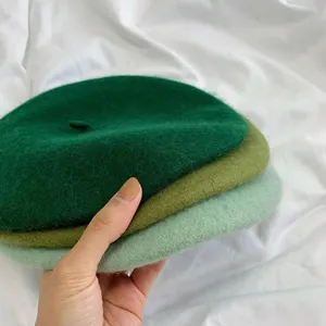 Detailed macro view of three soft wool beret hats stacked in various green shades