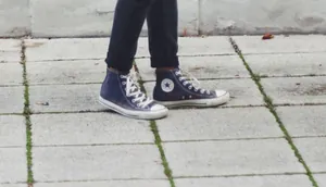 Primo piano di sneakers alte in tela blu scuro indossate su un marciapiede grigio