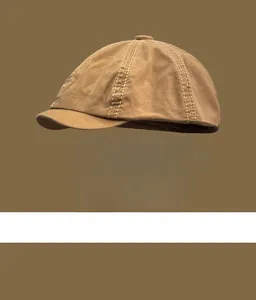 Close-up of a vintage British style brown newsboy cap with white stitching detail.