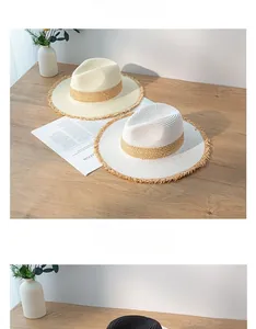 Two elegant summer straw fedoras with frayed edges and tan bands on a wooden table.