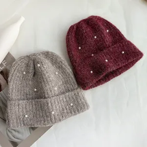Detailed view of burgundy and grey winter knitted beanies featuring delicate pearl accents.