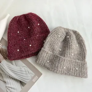 Elegant winter knitted beanies featuring delicate pearl beads in burgundy and warm beige colors