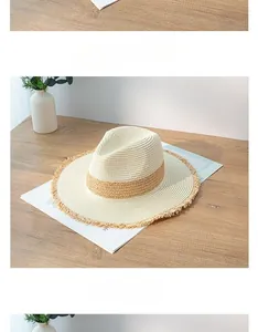 Detail view of a straw fedora hat with contrast band and frayed edges on a wood table.