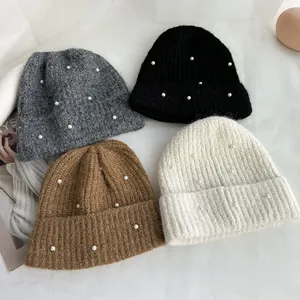 Detailed view of winter pearl-decorated knitted beanies in multiple soft, cozy colors.