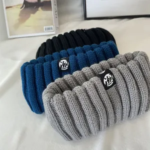 Close-up of three ribbed knit headbands in gray, blue, and black with trendy labels