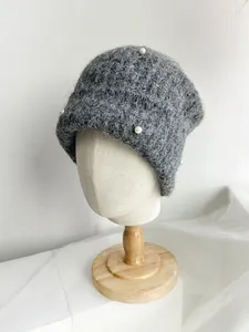 Detail view of grey knitted beanie with elegant pearl decorations and fuzzy texture