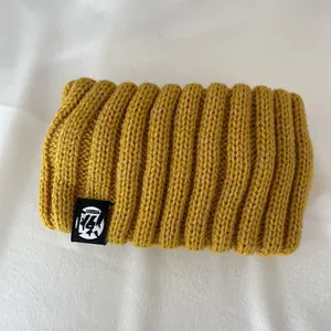 Close-up of thick mustard yellow ribbed knit headband with woven logo tag detail