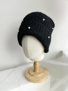 Detailed view of a black knit beanie with elegant white pearl embellishments