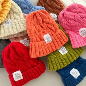 Dettaglio di vari berretti colorati in maglia a trecce con etichette bianche alla moda