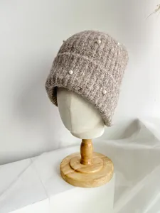 Detailed close-up of a knitted beanie with elegant pearl accents and soft wool texture.
