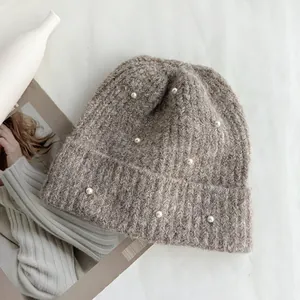 Close-up of a stylish brown knitted beanie hat with elegant pearl decorations for winter.