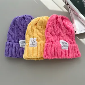 Vista dettagliata di berretti in maglia a trecce color caramella con etichette
