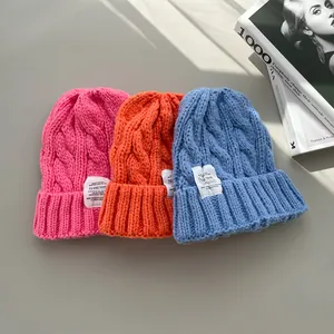 Dettaglio di tre berretti in maglia a trecce dai colori vivaci per il calore invernale.