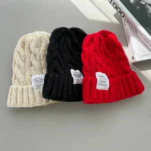 Vista dettagliata di berretti in maglia a trecce nei colori crema, nero e rosso per l'inverno