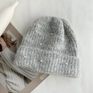 Detailed close-up view of a grey knitted winter beanie with elegant pearl decorations