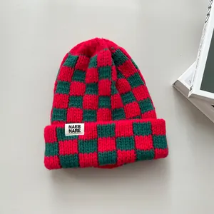 Close-up of red and green checkered knitted beanie hat with white brand patch