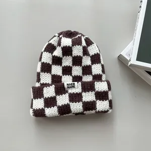 Detailed close-up texture of a brown and white checkerboard pattern knitted beanie hat