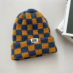 Close-up of yellow and blue checkerboard knit beanie showing thick woolen texture.