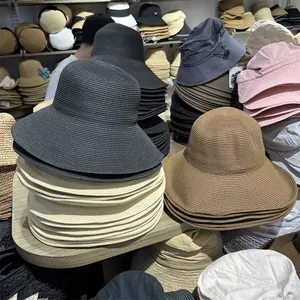 Various colors of foldable wide-brim straw sun hats stacked in a retail display.
