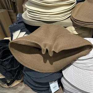 Detailed macro view of foldable woven straw sun hats in various natural earth tones.