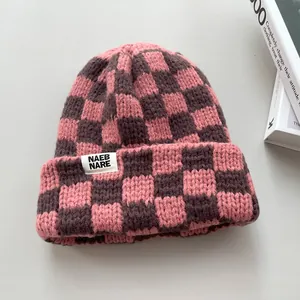 Detailed macro shot of a pink and brown checkered thick knit winter warm beanie hat