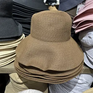 Close-up of foldable wide-brimmed straw sun hat showing woven texture and various color options.